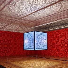 large, laser-cut steel cube suspended from the gallery ceiling fills the space with elaborate floor-to-ceiling shadows